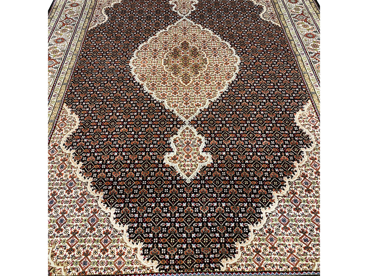 Brown Indo-Tabriz rug detail: fine pattern in the dark field with a light center