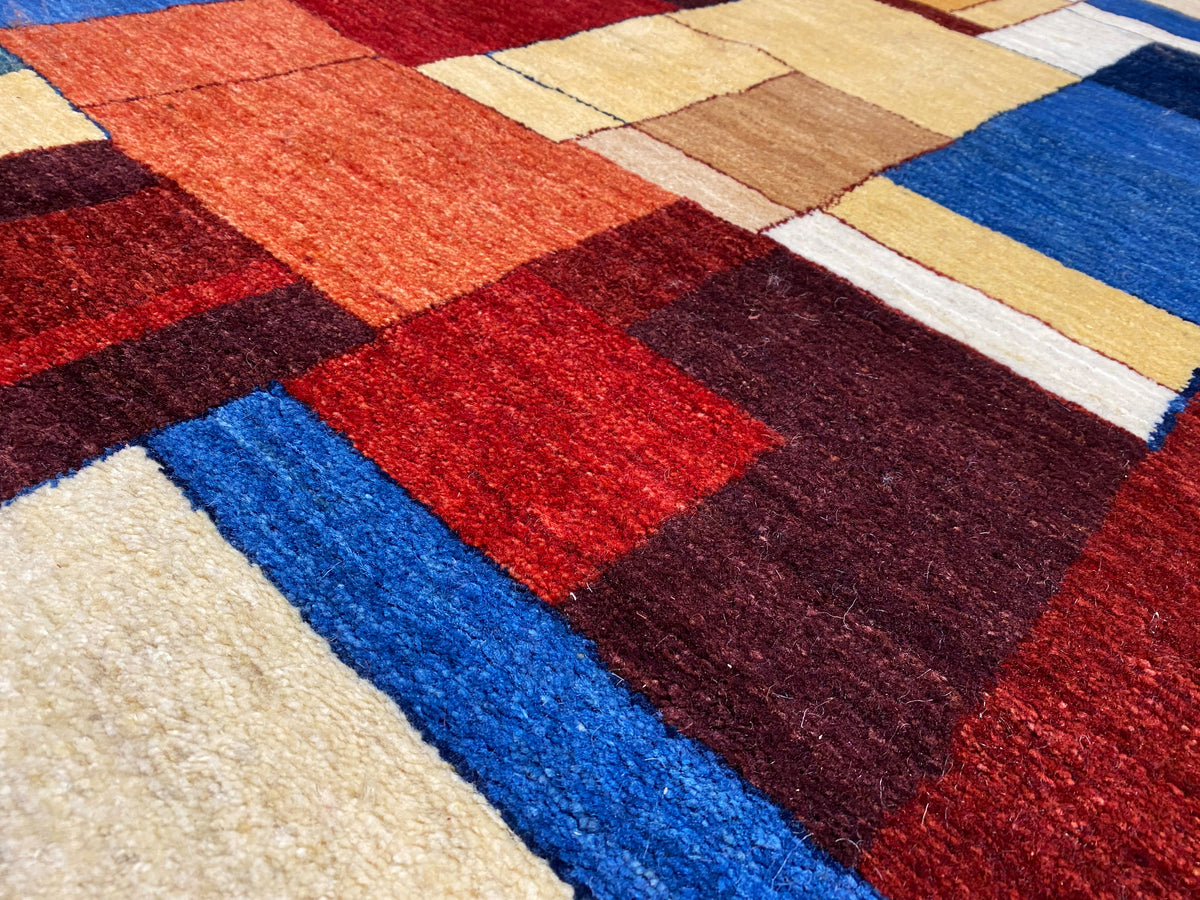 Gabbeh-Luri-Teppich Nahaufnahme: kräftige Farbkacheln in Rot, Blau, Dunkelbraun und Beige.