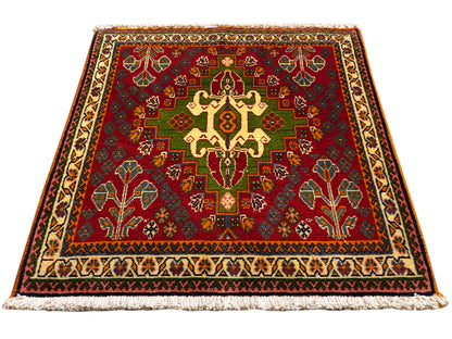 Oriental rug with a red central motif, green details, and a beige border, with fringe