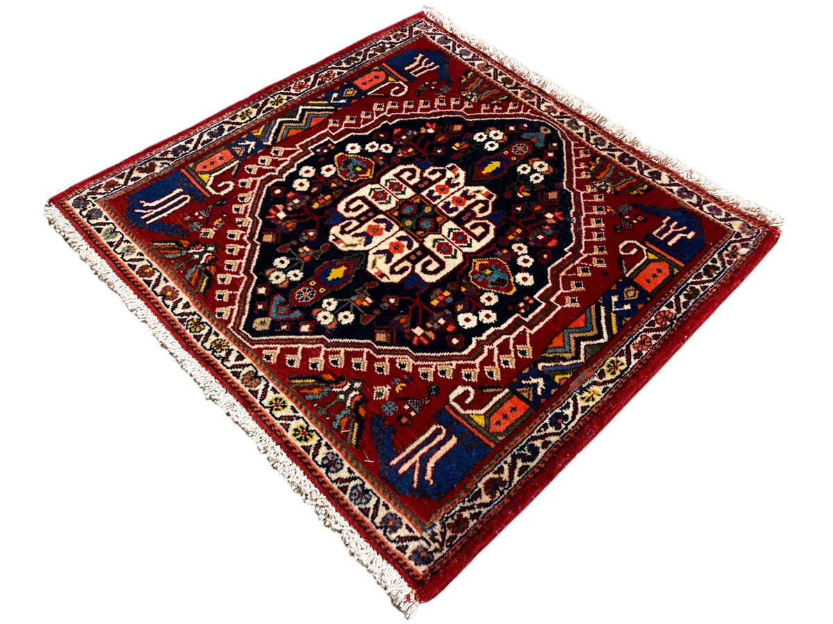 Rug with a red border and dark blue center, star-shaped ornament, fringe